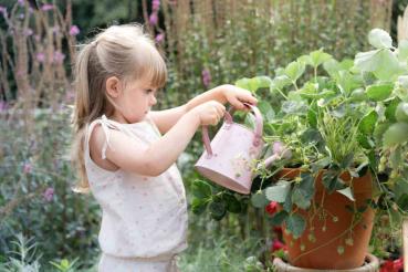 Kind hält die rosa Fairy Garden Gießkanne von Little Dutch im Garten