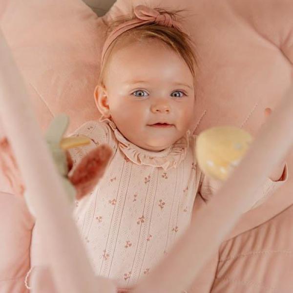 Baby liegt auf rosa Spieldecke mit Greifanhängern in Blüten-Optik von Little Dutch